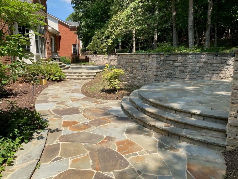 Landscape featuring a stone pathway and steps surrounded by greenery and trees.