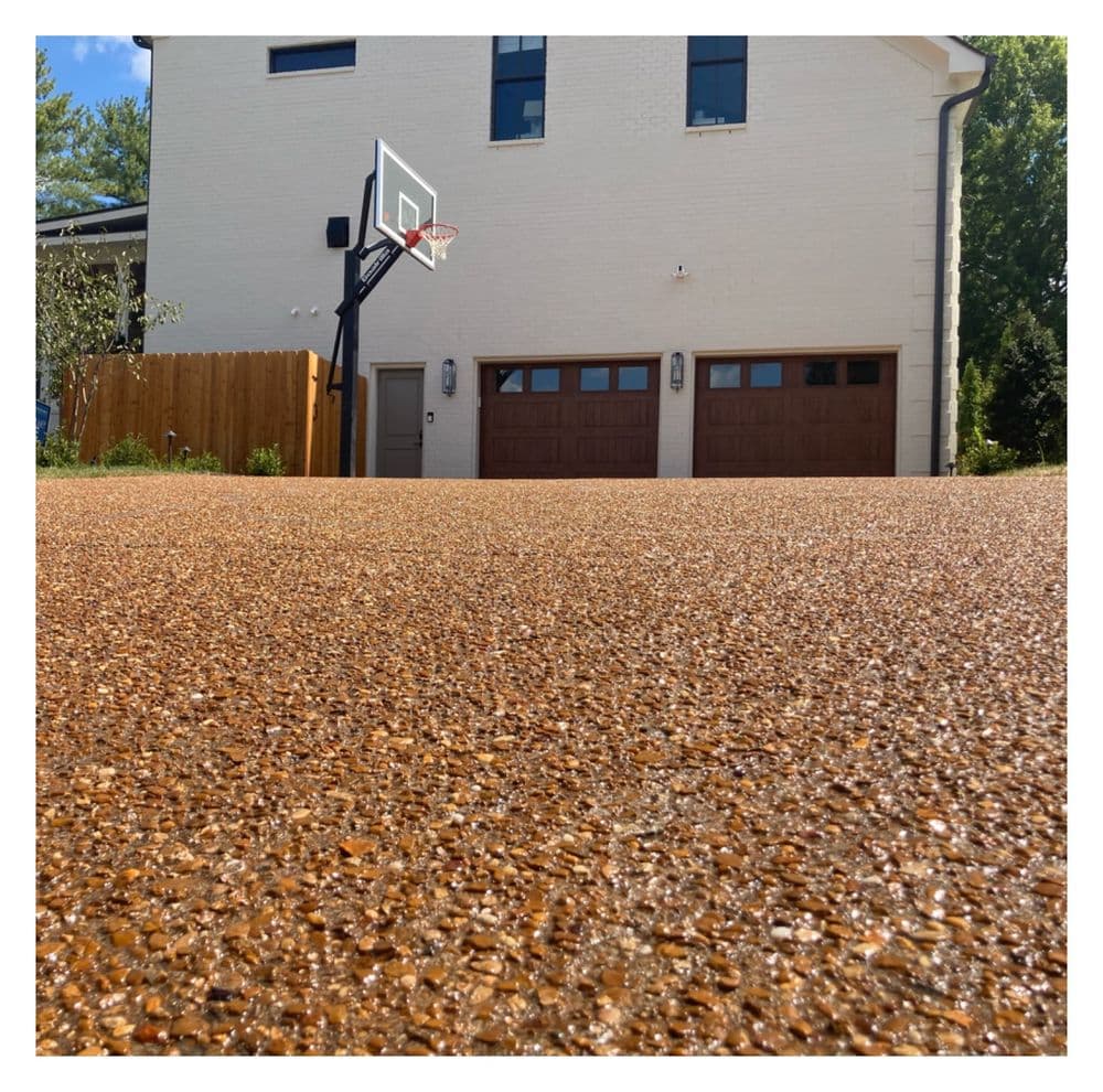 Home with a basketball hoop and textured driveway, showcasing a modern design.