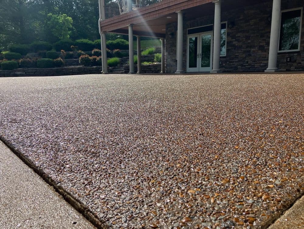 Decorative concrete patio with a stone texture, featuring a modern home in the background.