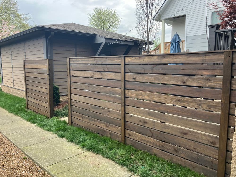 Wooden slatted fence in a residential area, enhancing privacy and aesthetic appeal.