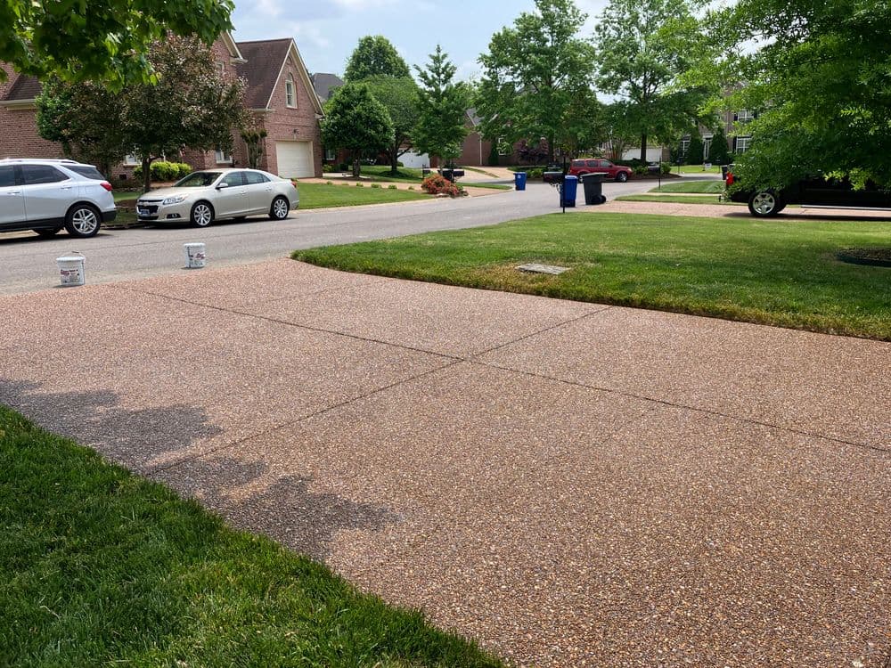 Freshly treated gravel driveway with parked cars and landscaped lawns on a suburban street.