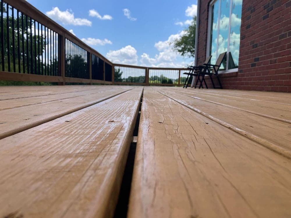 Wooden deck with a clear blue sky and white clouds in the background, featuring outdoor seating.