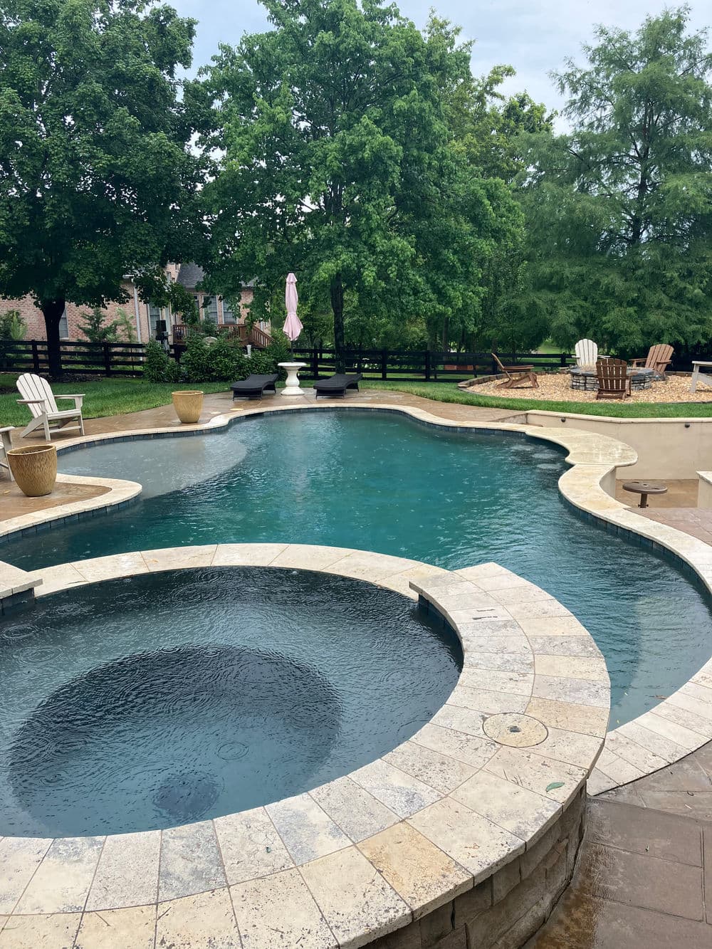 Elegant outdoor pool surrounded by greenery and patio furniture, perfect for relaxation.