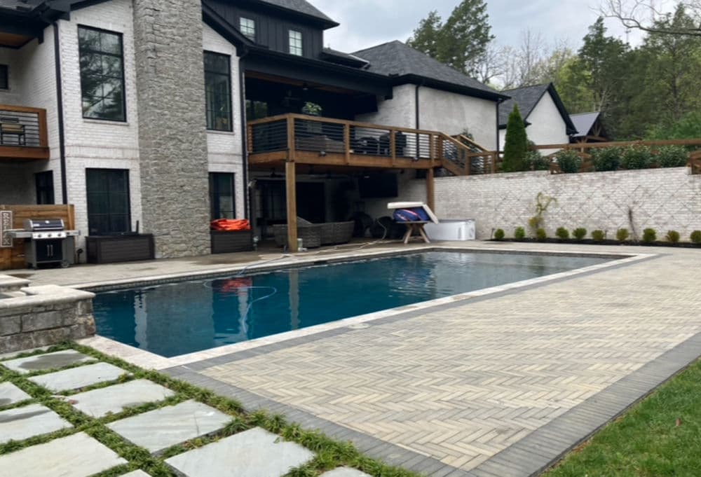 Modern home with stone accents featuring a backyard pool and patio area.