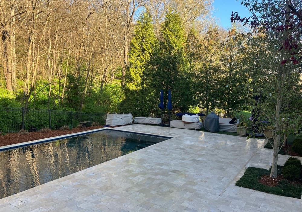Modern backyard with a swimming pool, lush greenery, and cozy seating areas.