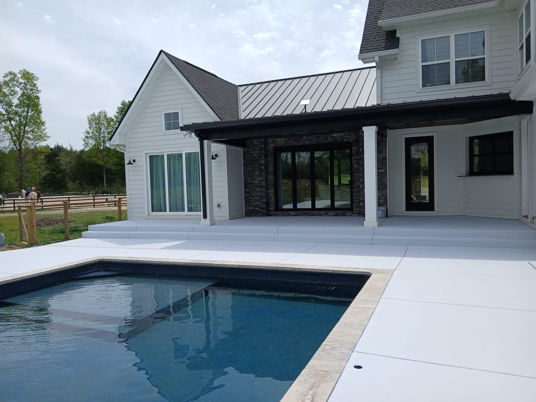 Modern home exterior with a pool, patio, and scenic backyard view on a sunny day.