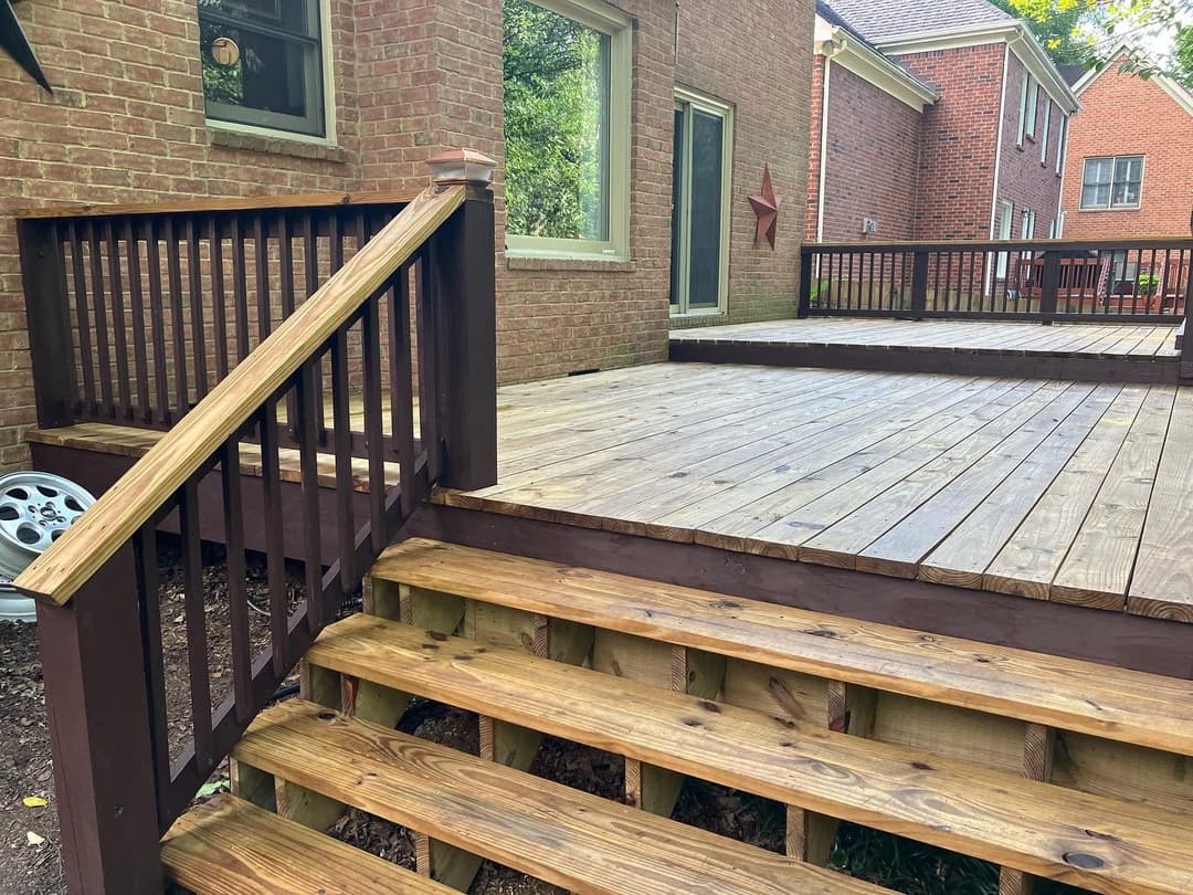 Outdoor wooden deck with stairs, featuring a modern design and surrounded by brick houses.