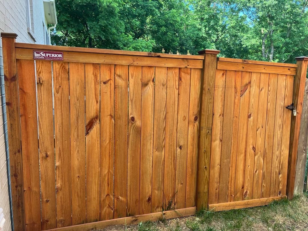 Wooden privacy fence with clean lines and a "Superior" sign, surrounded by greenery.