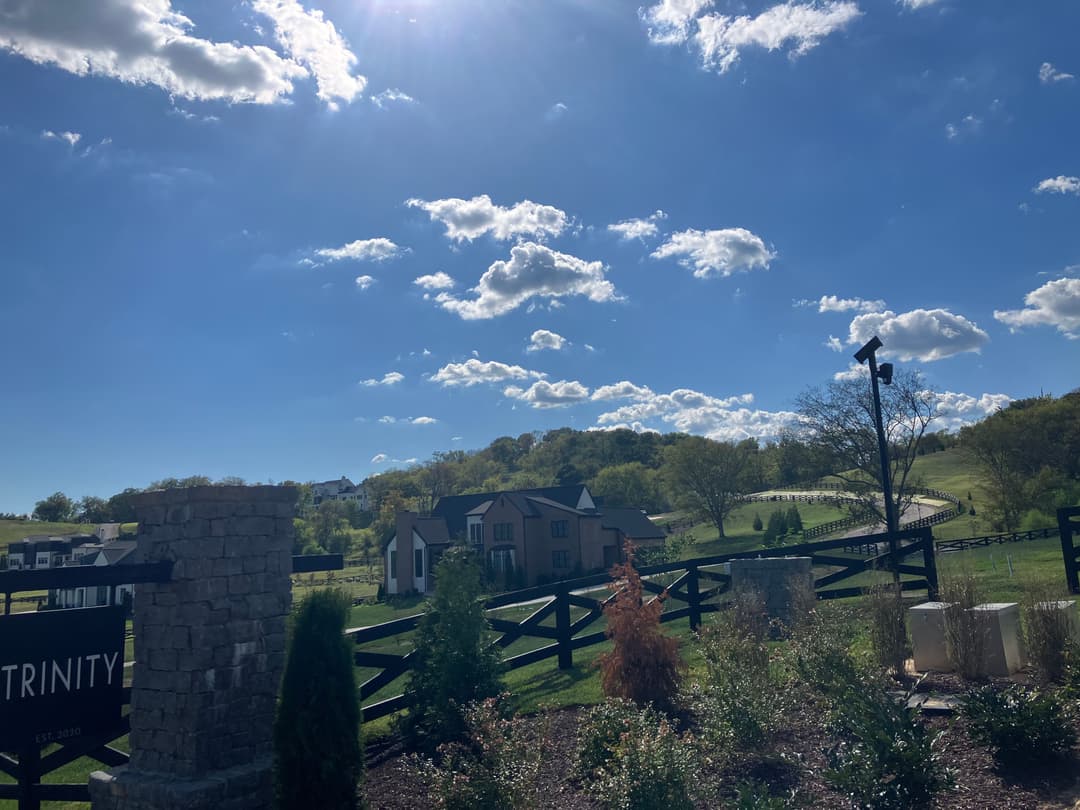 Trinity community with scenic hills, blue sky, and fluffy clouds in the background.