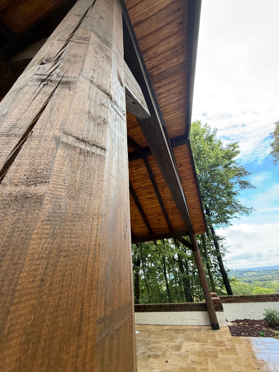 Close-up of a wooden support beam under a patio, showcasing rustic design and scenic views.
