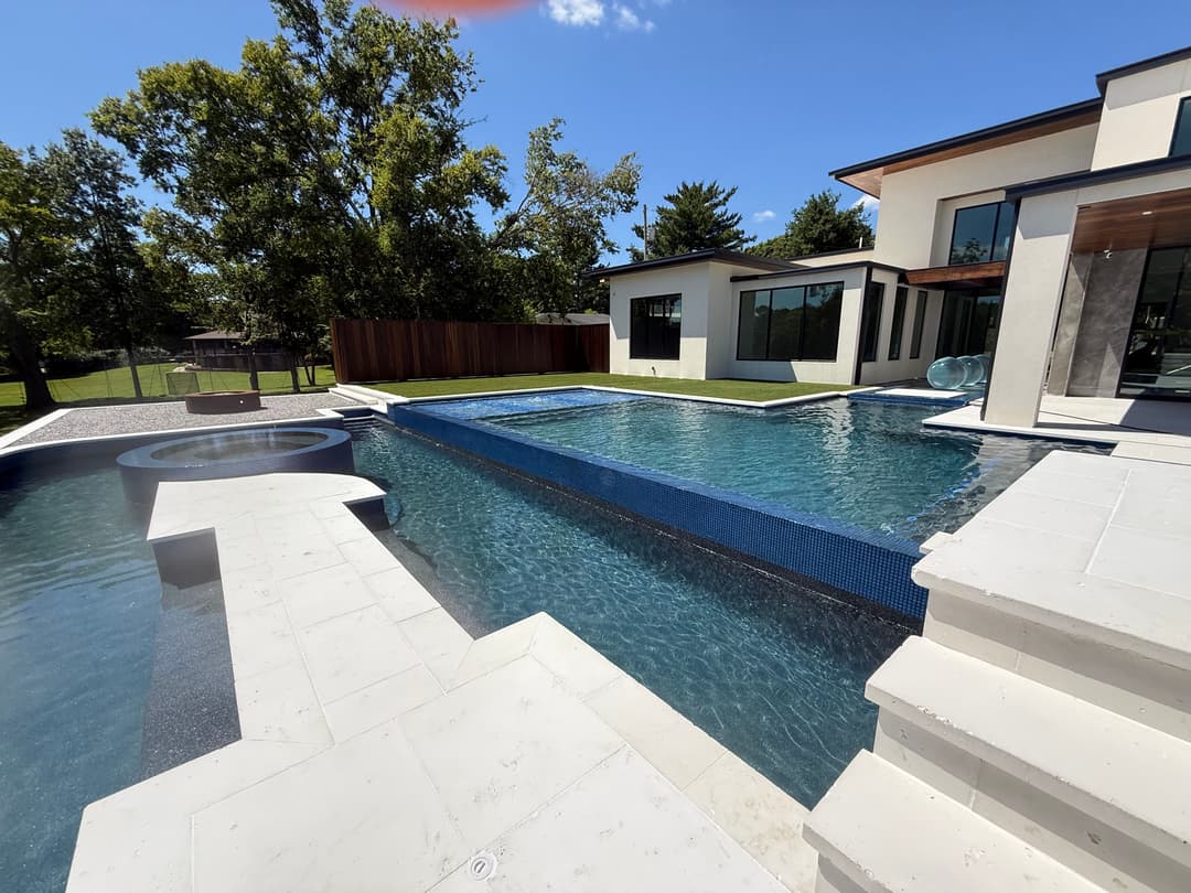 Luxurious modern home with a sparkling pool and spa surrounded by a landscaped yard.