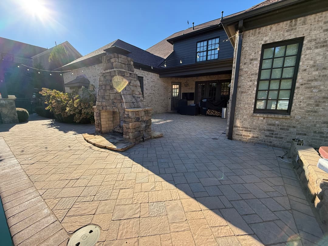 Backyard patio with stone fireplace and charming outdoor seating in sunlight.