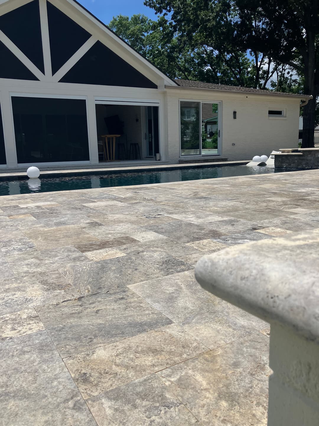 Modern home exterior with patio, pool, and large windows set in a lush green environment.