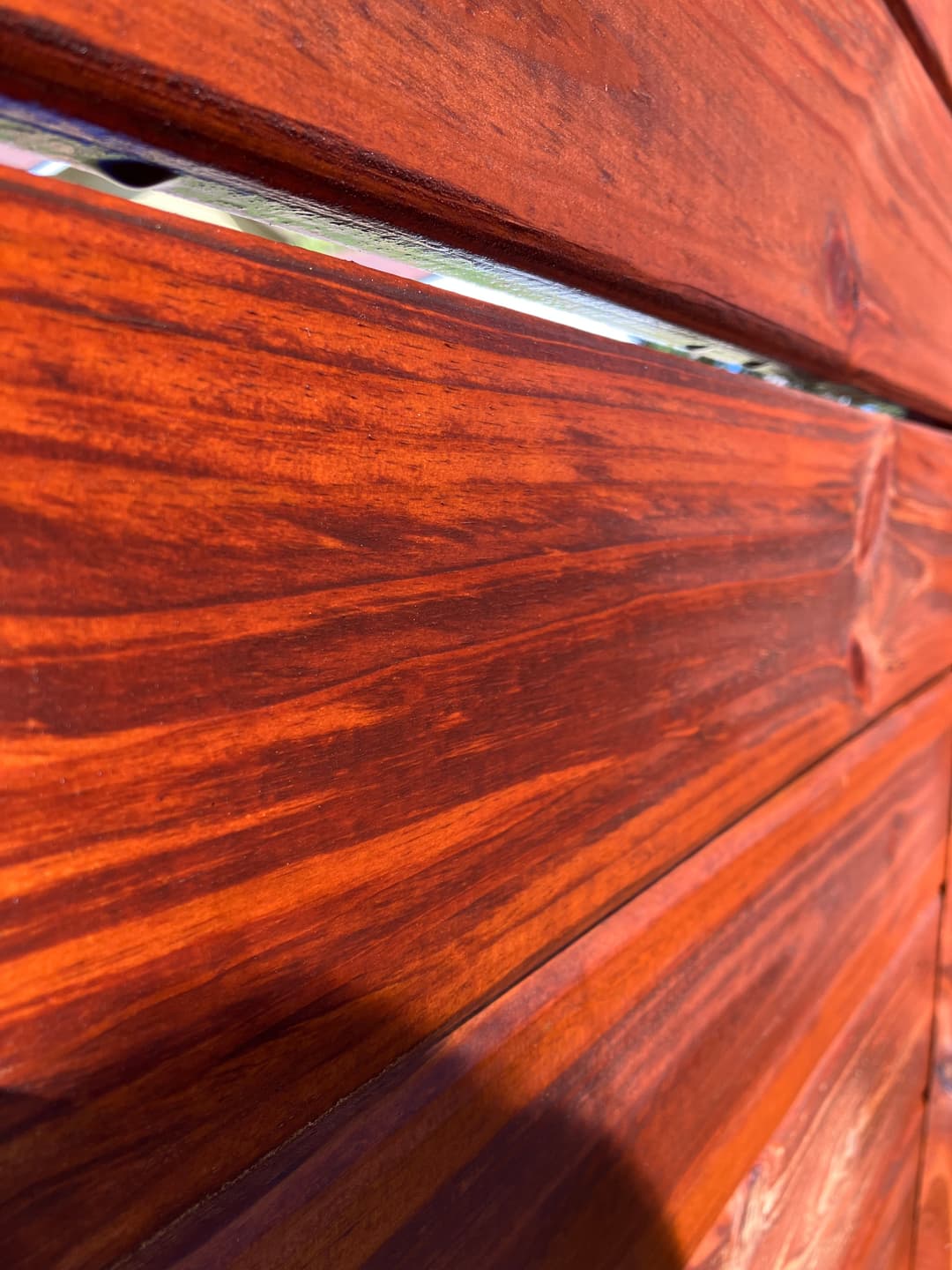 Close-up of polished wooden planks with rich reddish-brown finish and visible grain texture.
