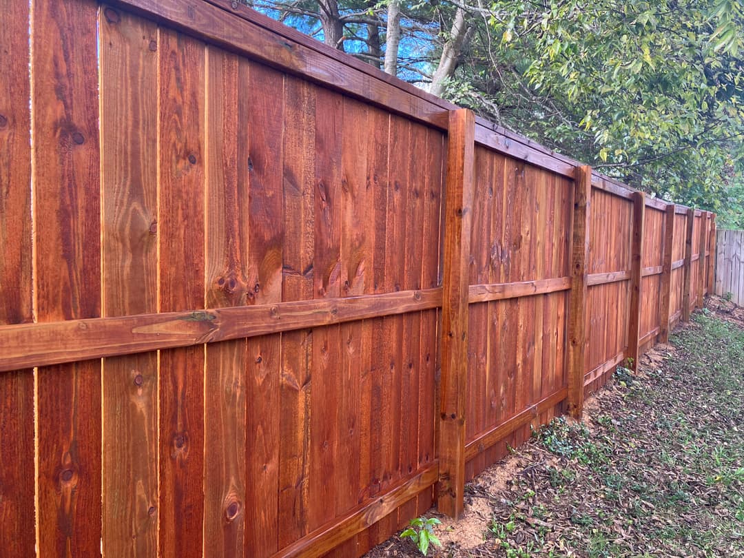 Stunning wooden privacy fence along a green yard with trees in the background.
