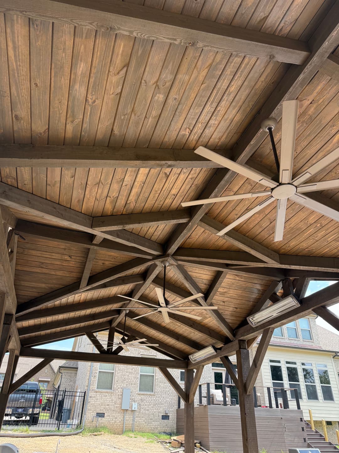 Wooden patio ceiling with exposed beams and ceiling fans, enhancing outdoor living space.