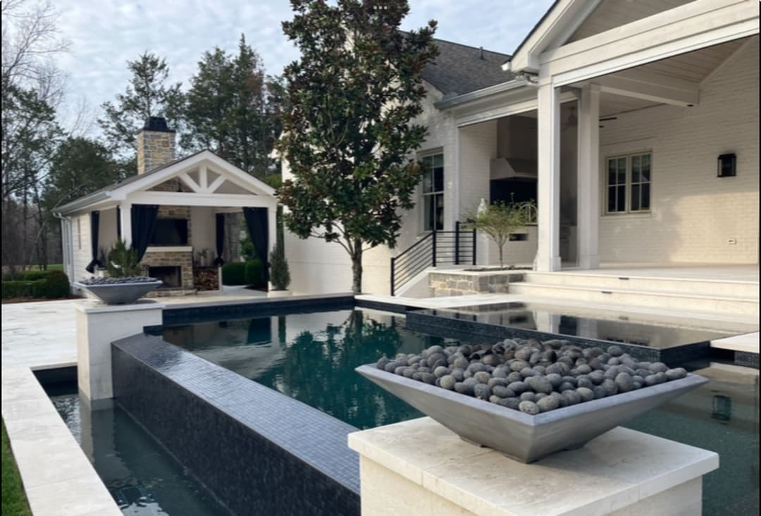 Luxury modern home exterior with a stylish pool, stone features, and landscaped garden.