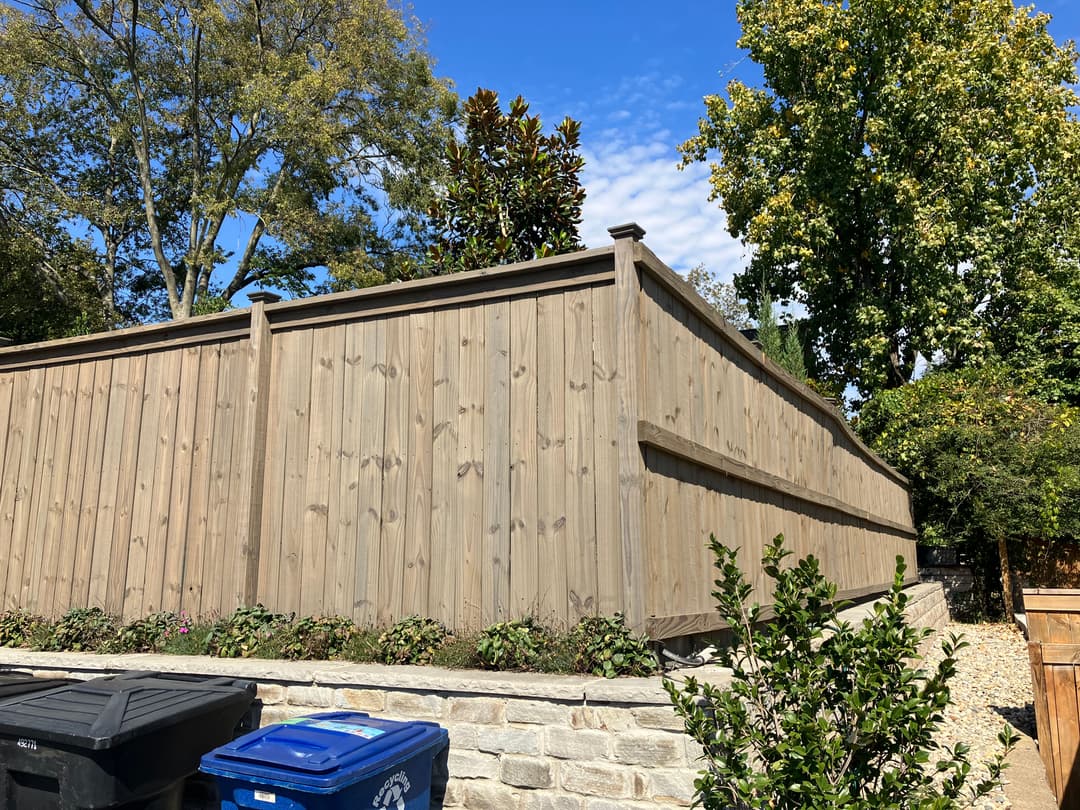Wooden privacy fence with landscaping and blue sky in the background.